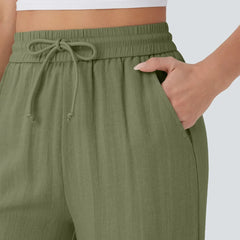 Close-up of olive green drawstring waist detail on wide-leg trousers.