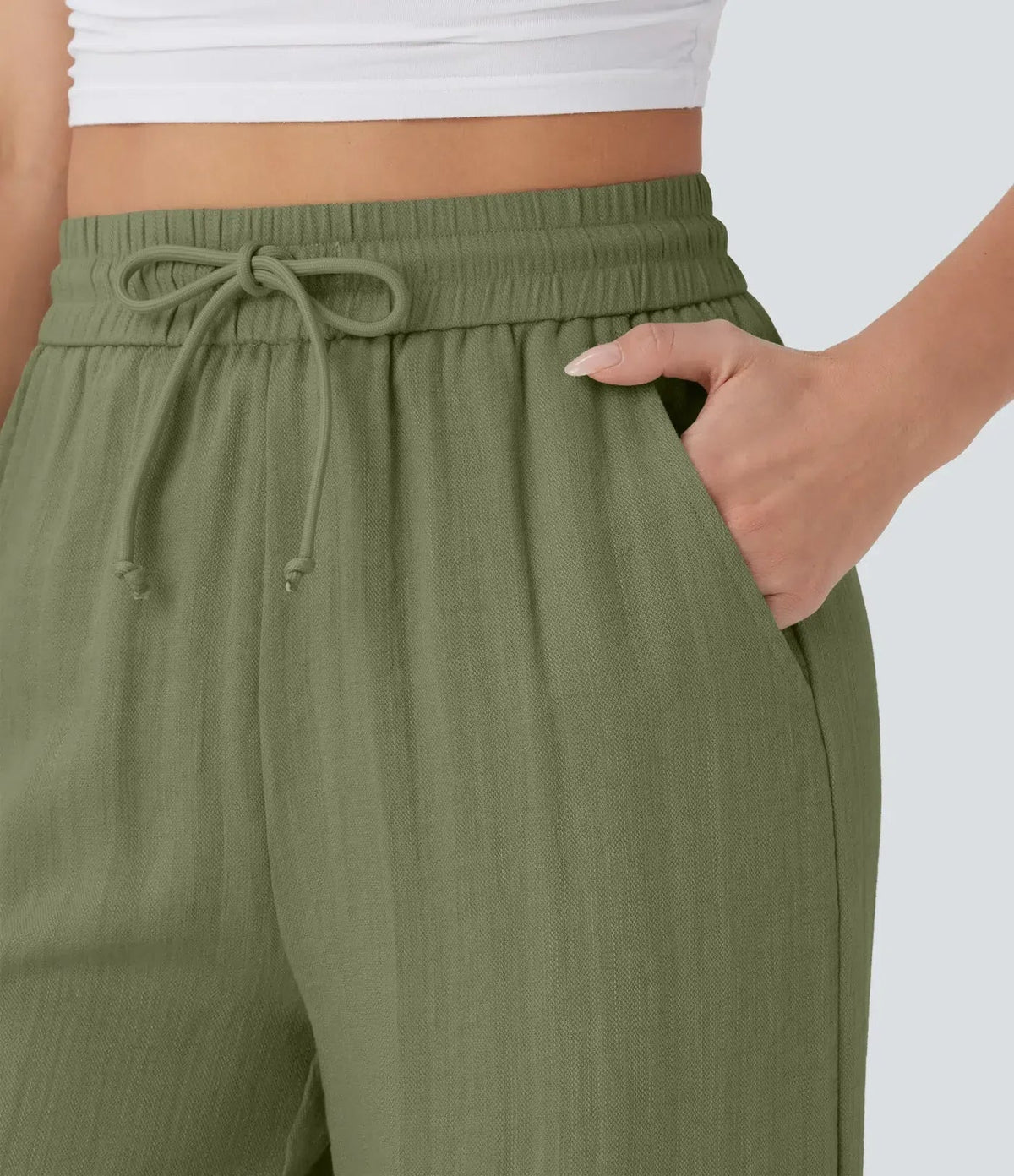 Close-up of olive green drawstring waist detail on wide-leg trousers.