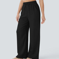 Black wide-leg trousers with elastic waistband and drawstring, full-length drape.