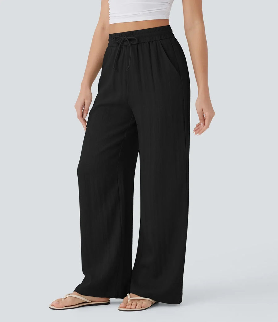 Black wide-leg trousers with elastic waistband and drawstring, full-length drape.