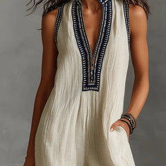 Beige sleeveless high-collar jumpsuit with zip placket and navy embroidered border