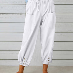 White relaxed-fit trousers with elastic waist, drawstring, side pockets, button cuff hem.