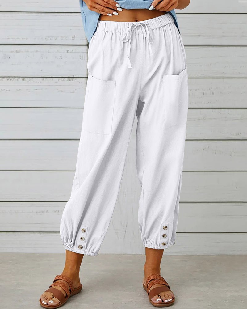 White relaxed-fit trousers with elastic waist, drawstring, side pockets, button cuff hem.