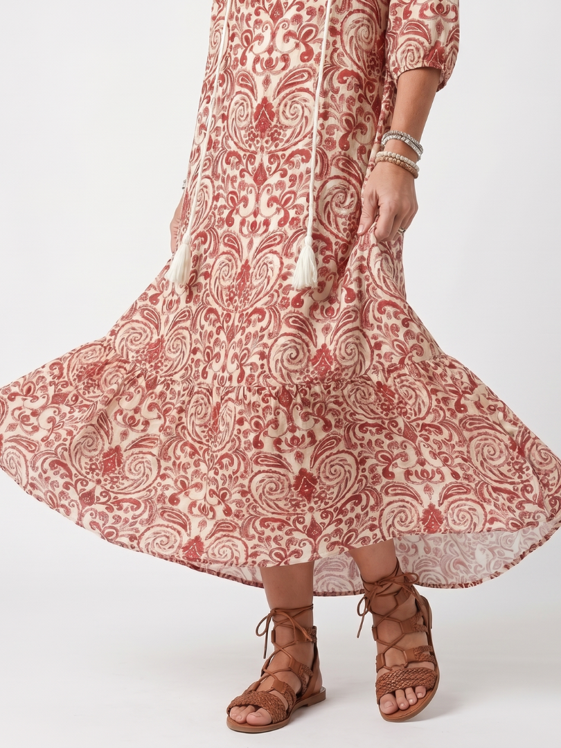 Red ornate print midi dress with full skirt flare and detailed hem, close-up