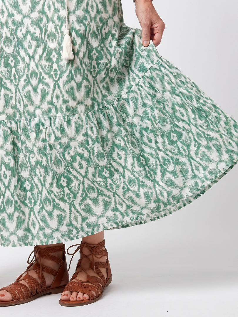 Green patterned midi dress fabric close-up with gathered tiered hem
