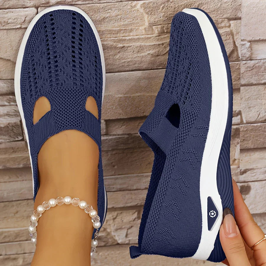 Navy knit slip-on sneakers with side cutouts and white cushioned soles