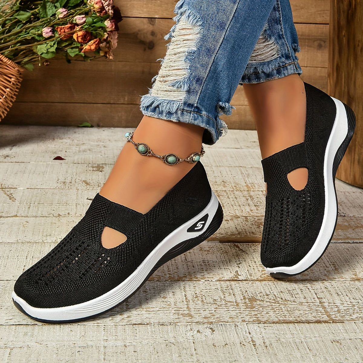 Black knit slip-on sneakers with side cutouts and white cushioned soles