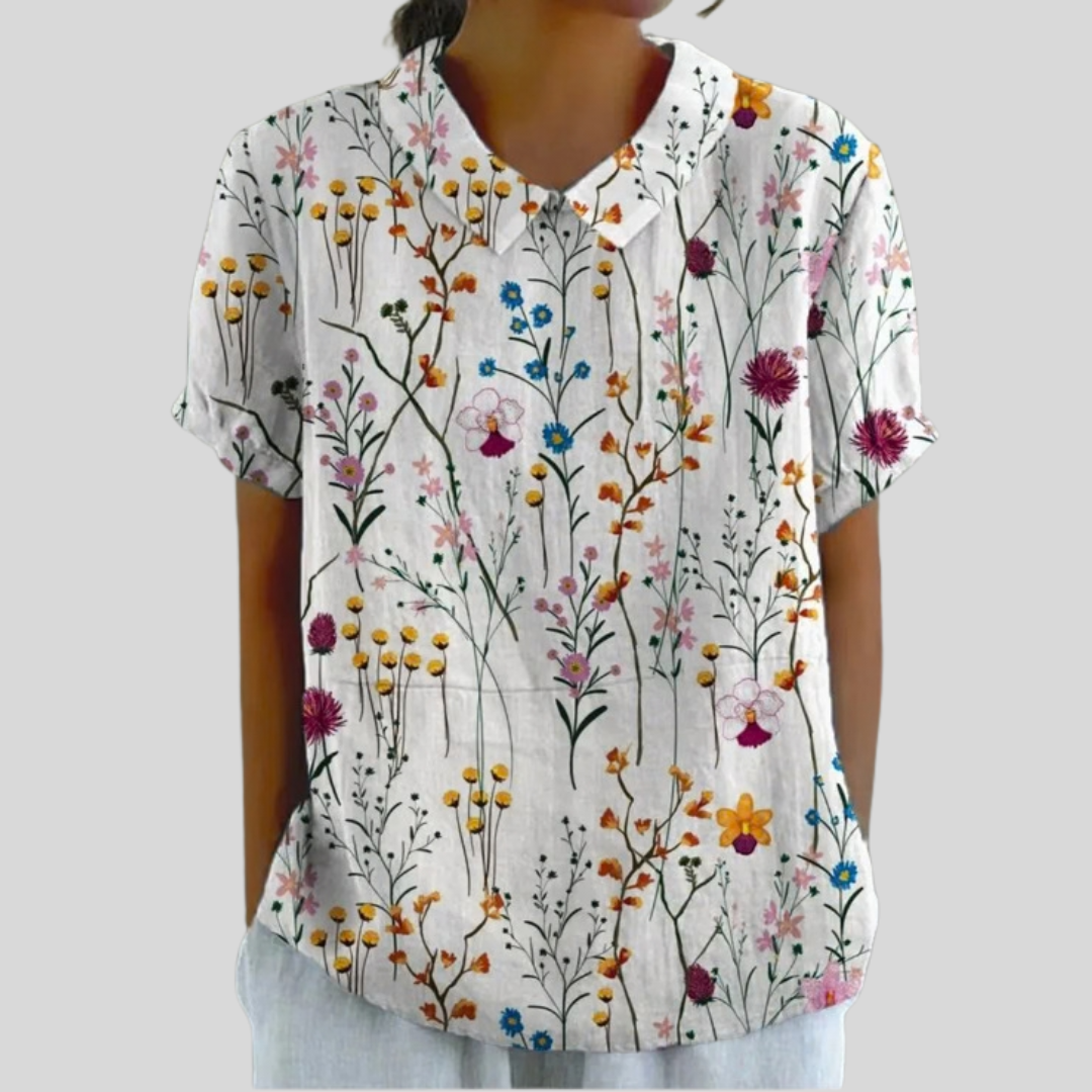 Top leggero bianco con stampa floreale colorata, scollo a V e maniche corte.