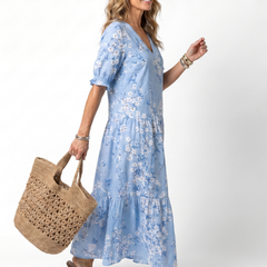 Blue floral midi dress with V-neck, short puff sleeves, and flowing tiered skirt