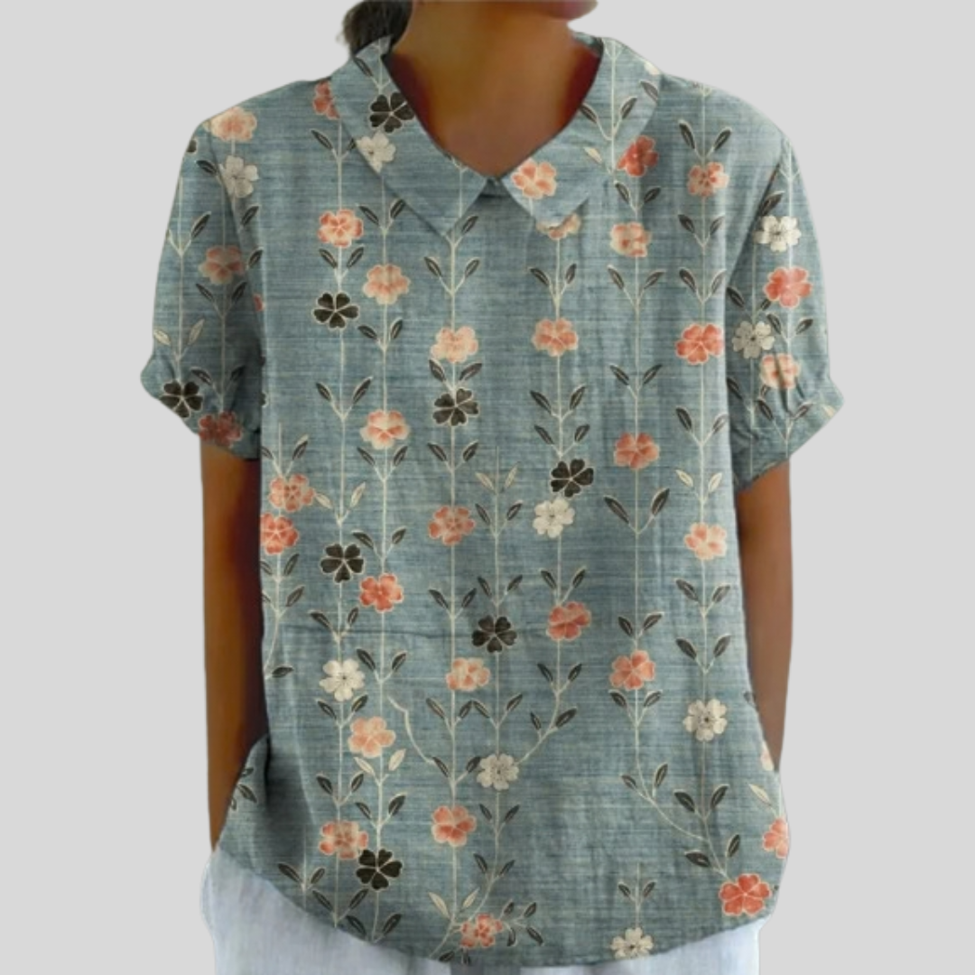 Top floreale con scollo a V, maniche corte, base verde azzurra con fiori arancio e crema.