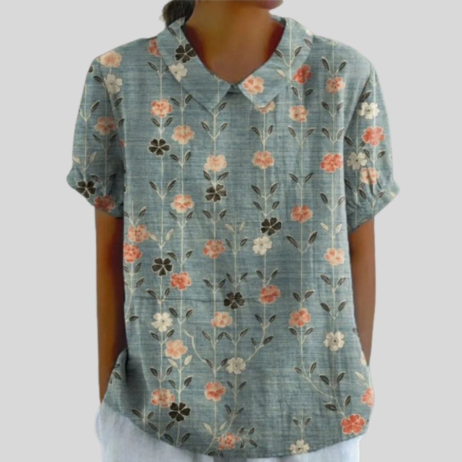 Top floreale con scollo a V, maniche corte, base verde azzurra con fiori arancio e crema.