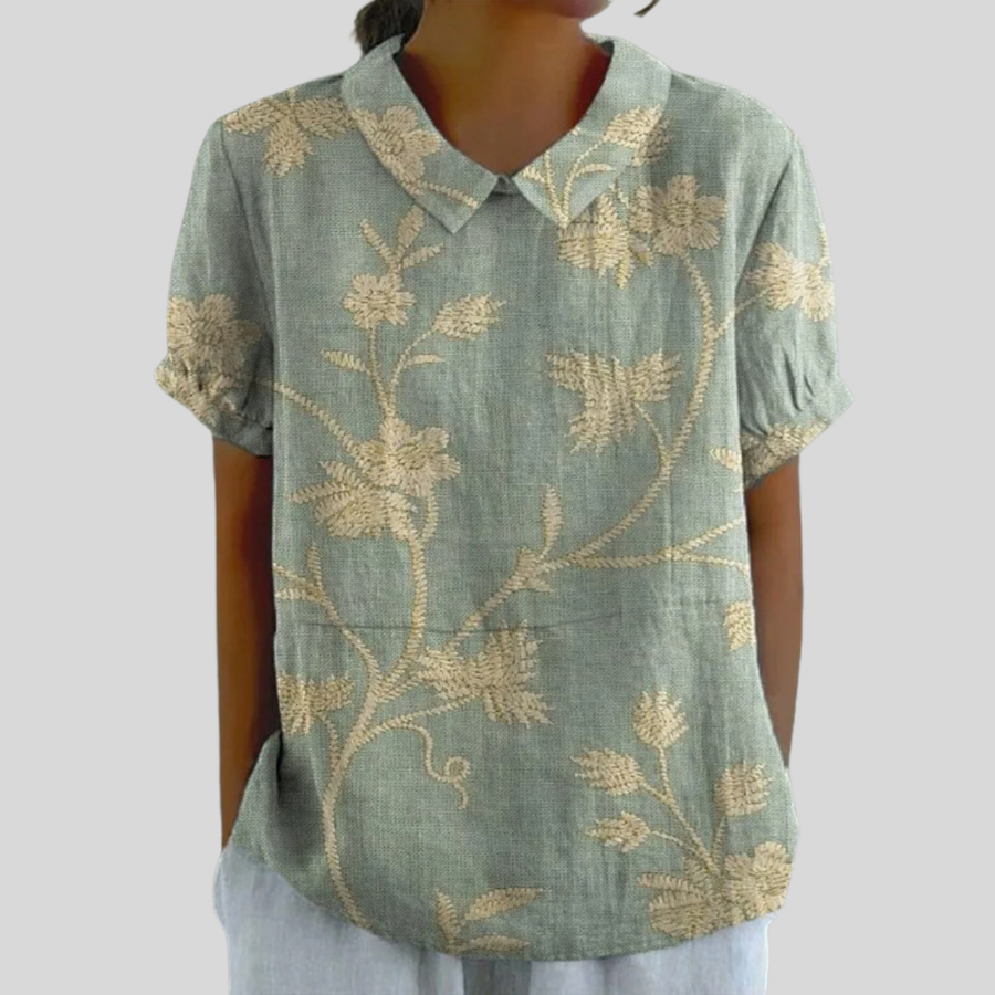 Top in tessuto azzurro con motivo floreale beige, scollo a V e maniche corte