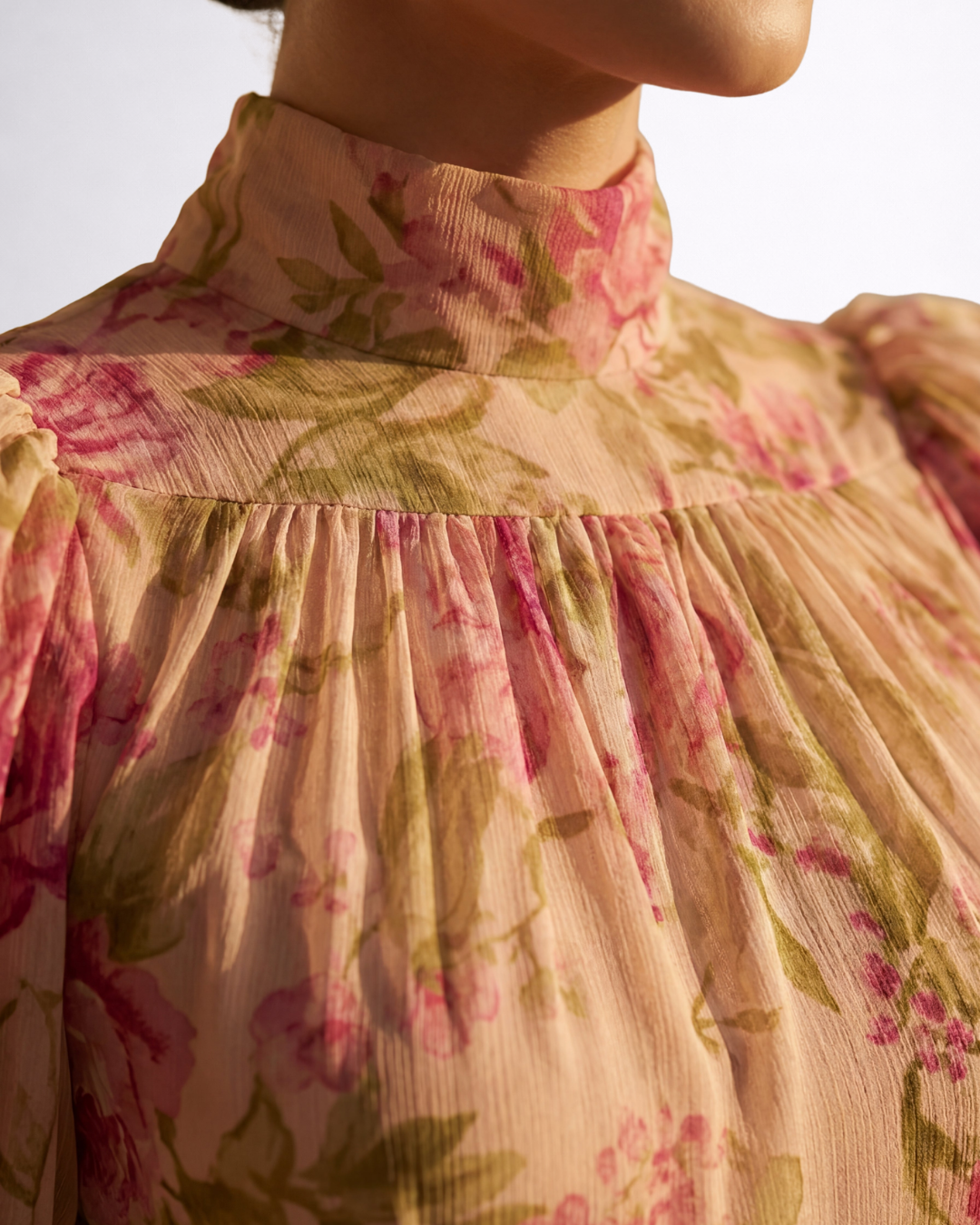 Dettaglio abito in chiffon floreale: collo alto e balze arricciate sul busto