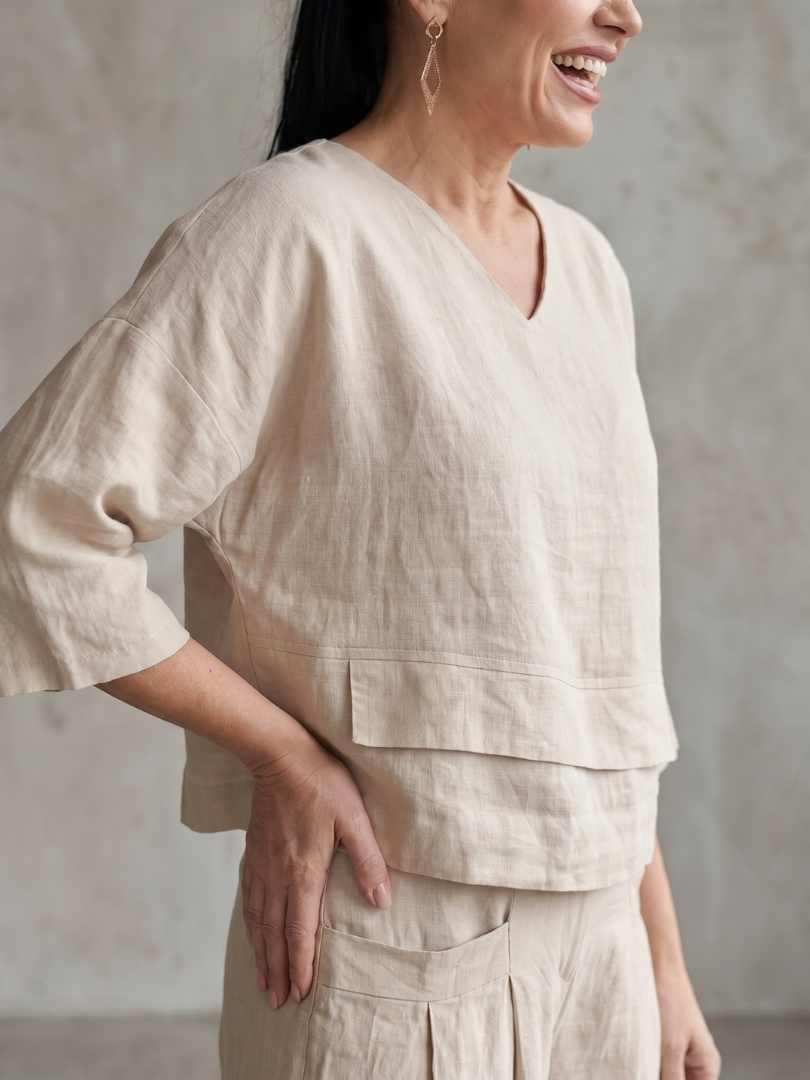Beige layered V-neck top with tiered hem detail, matching wide-leg pants