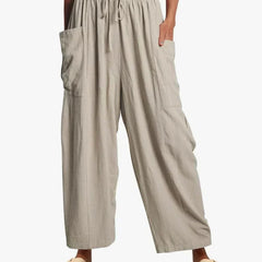 Light gray wide-leg trousers with elastic waist and drawstring, side cargo pockets.