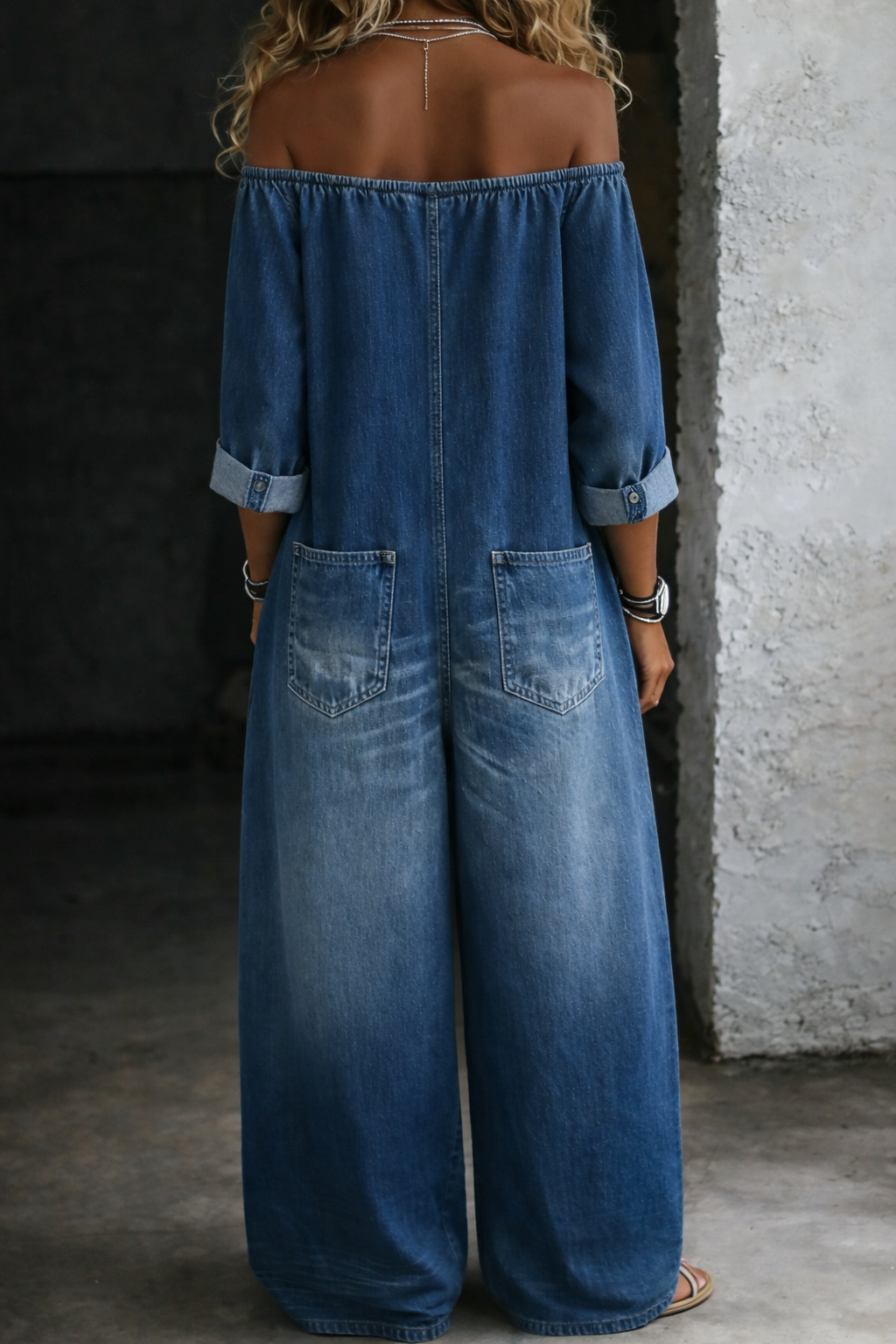 Blue denim overall, off-shoulder neckline, button front, back view with side pockets