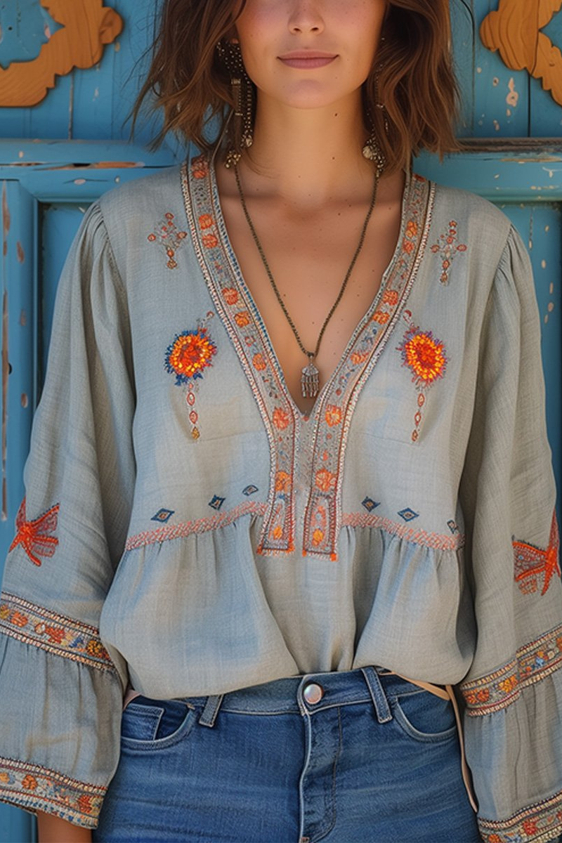 Light blue boho embroidered V-neck blouse with long puff sleeves and orange floral trim