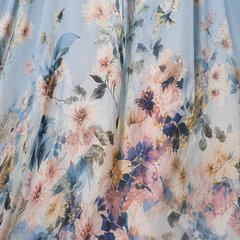 Abito lungo azzurro: dettaglio tessuto con fiori e foglie pastello, stampa multicolore.