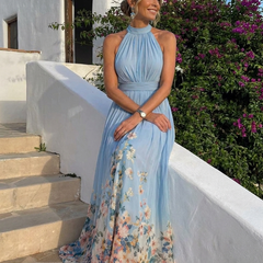 Abito lungo azzurro senza maniche con scollo halter e gonna ampia con fiori chiari.