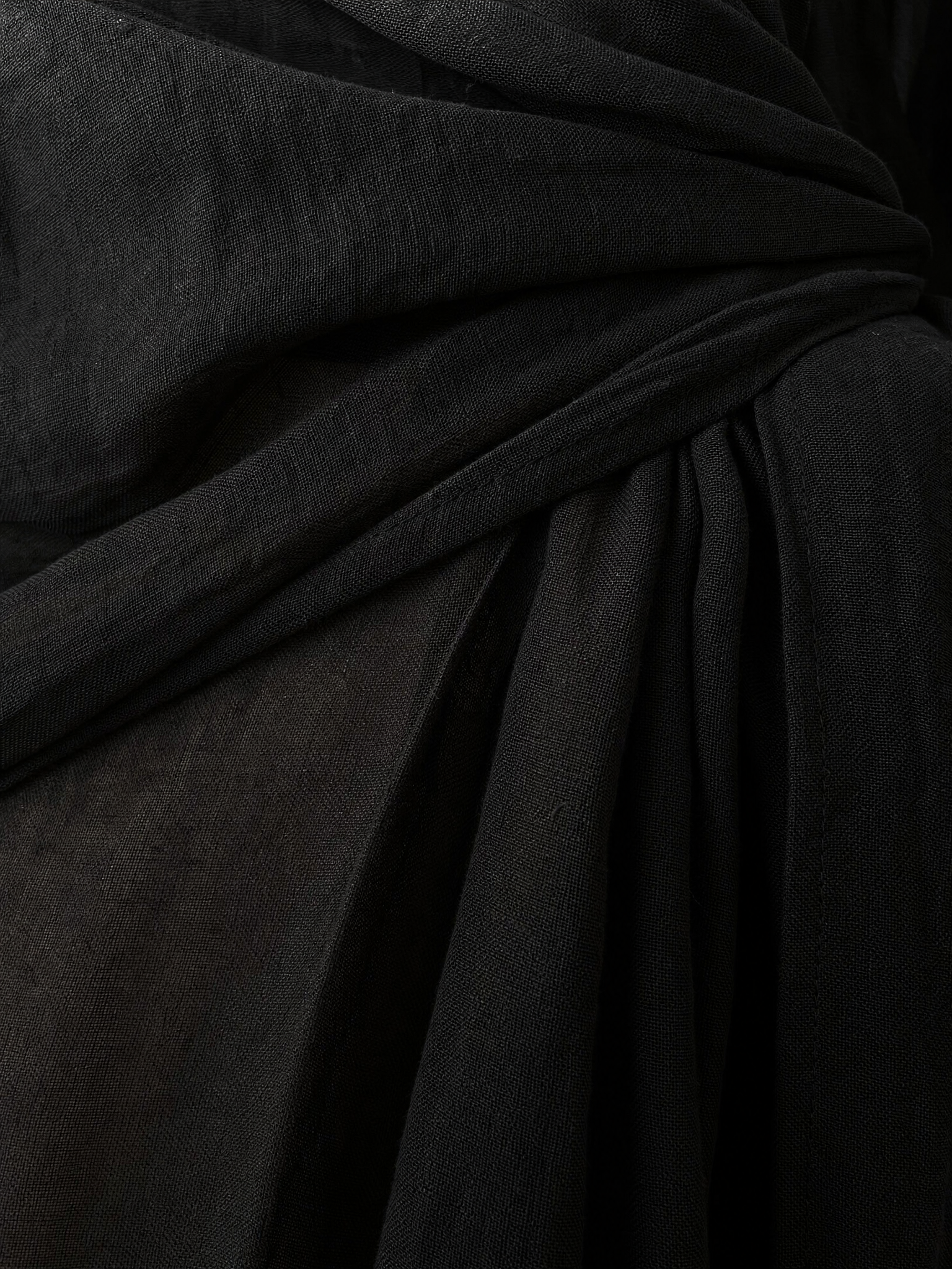 Close-up of black linen-blend fabric with textured weave and flowing folds