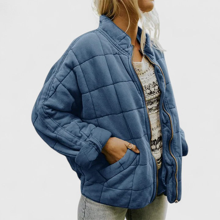 Quilted blue zip-up jacket with stand collar and side pockets, long sleeves