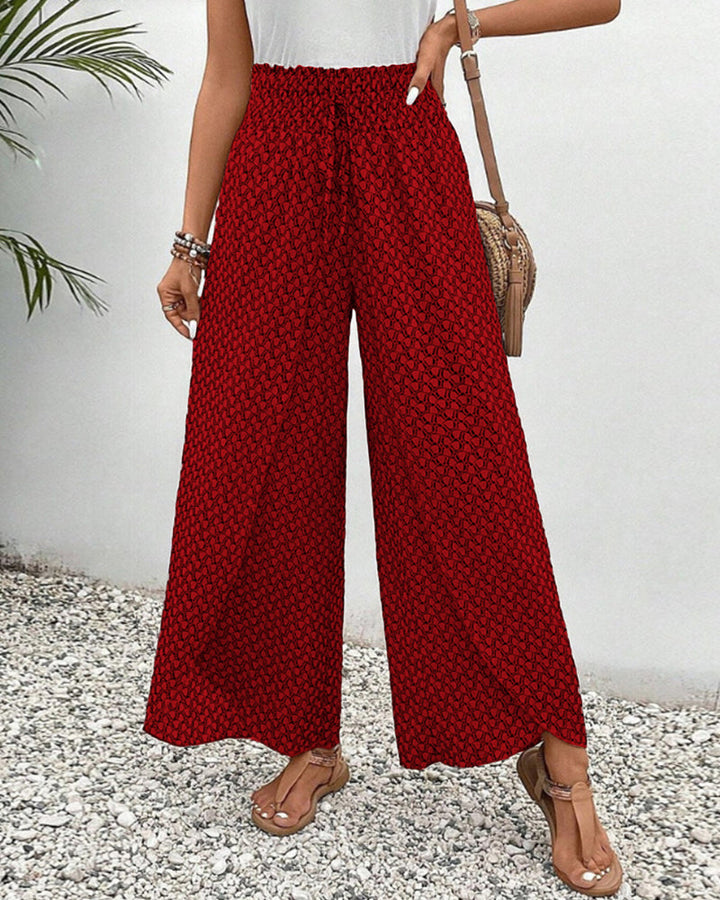 Red wide-leg trousers with shirred waistband and allover micro pattern, ankle length.