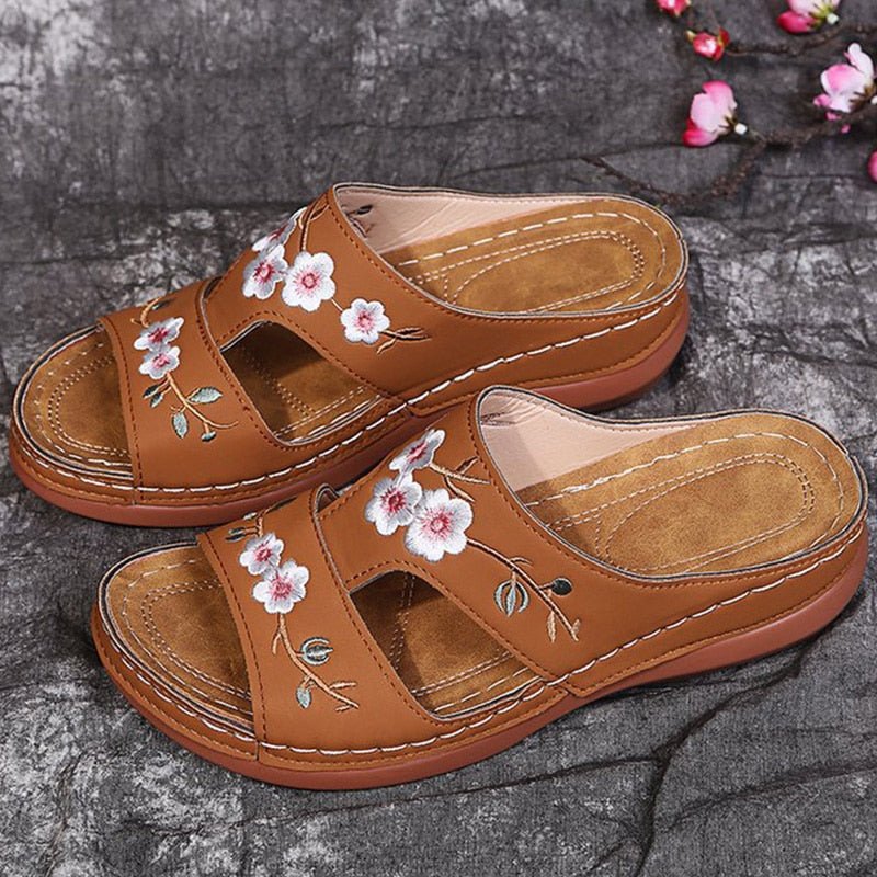 Sandali ortopedici marroni con cinturini e fiori bianchi ricamati, cuciture perimetrali.