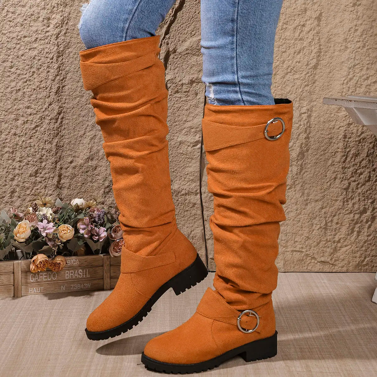 Knee-high orange suede boots with round buckle ring straps and lug sole