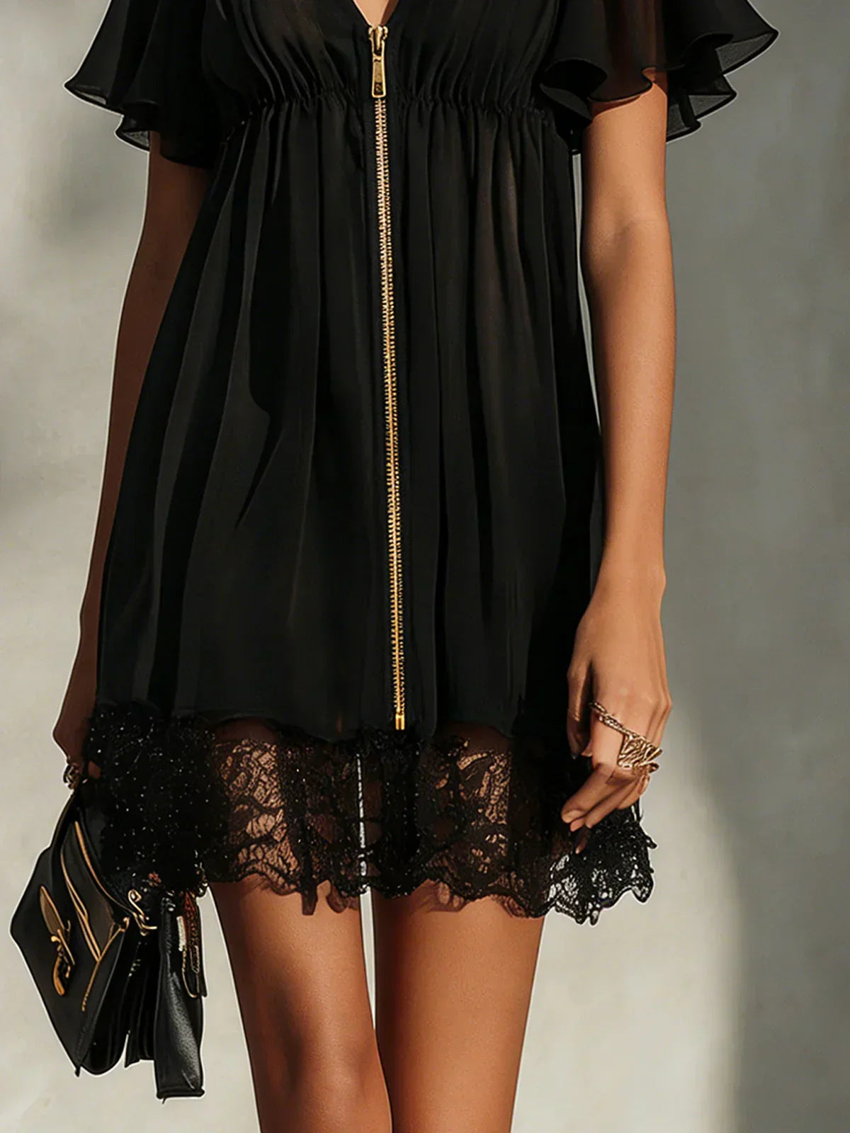 Black zip-front mini dress close-up: gold zipper and lace hem trim