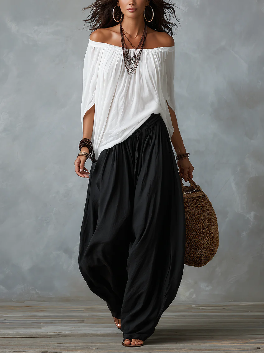 Completo con top bardot bianco drappeggiato e pantaloni ampi neri