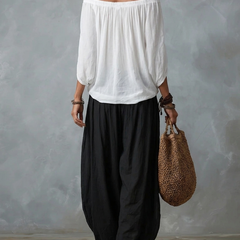 Completo con top bardot bianco e pantaloni ampi neri, vista posteriore