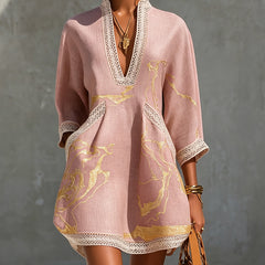 Pink lace midi dress with V-neck and lace trim, featuring gold abstract print