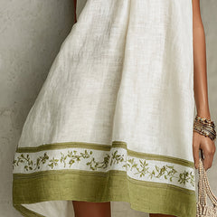 White midi dress with green floral hem band and draped sleeveless silhouette