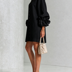 Black button-front midi dress, side view, puff sleeves with rosette cuffs