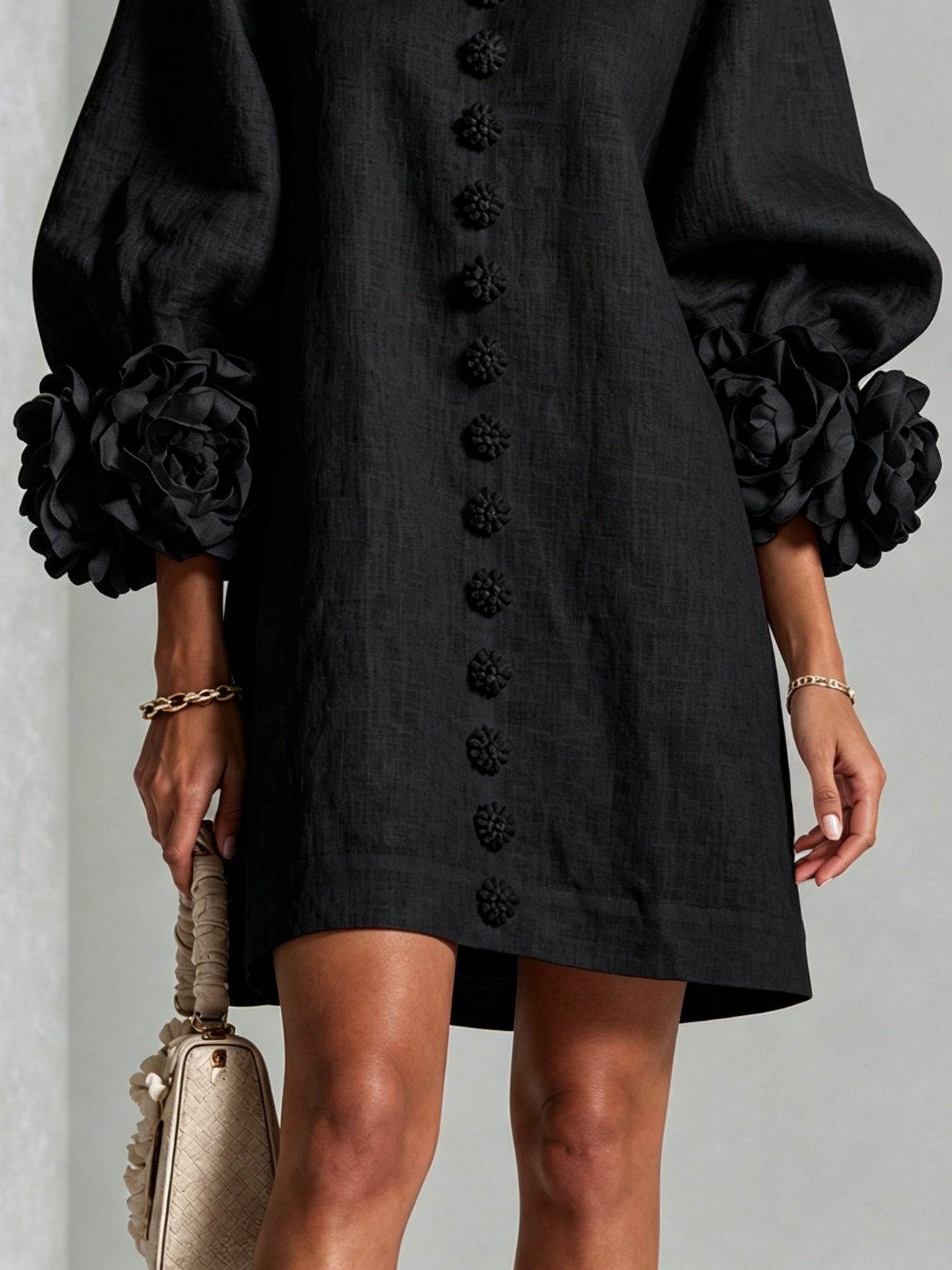 Black button-front midi dress hem view with floral front detail and rosette puff cuffs