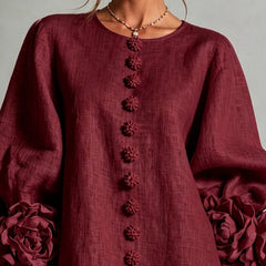 Close-up of burgundy midi dress: round neckline, textured fabric, and vertical embroidered trim