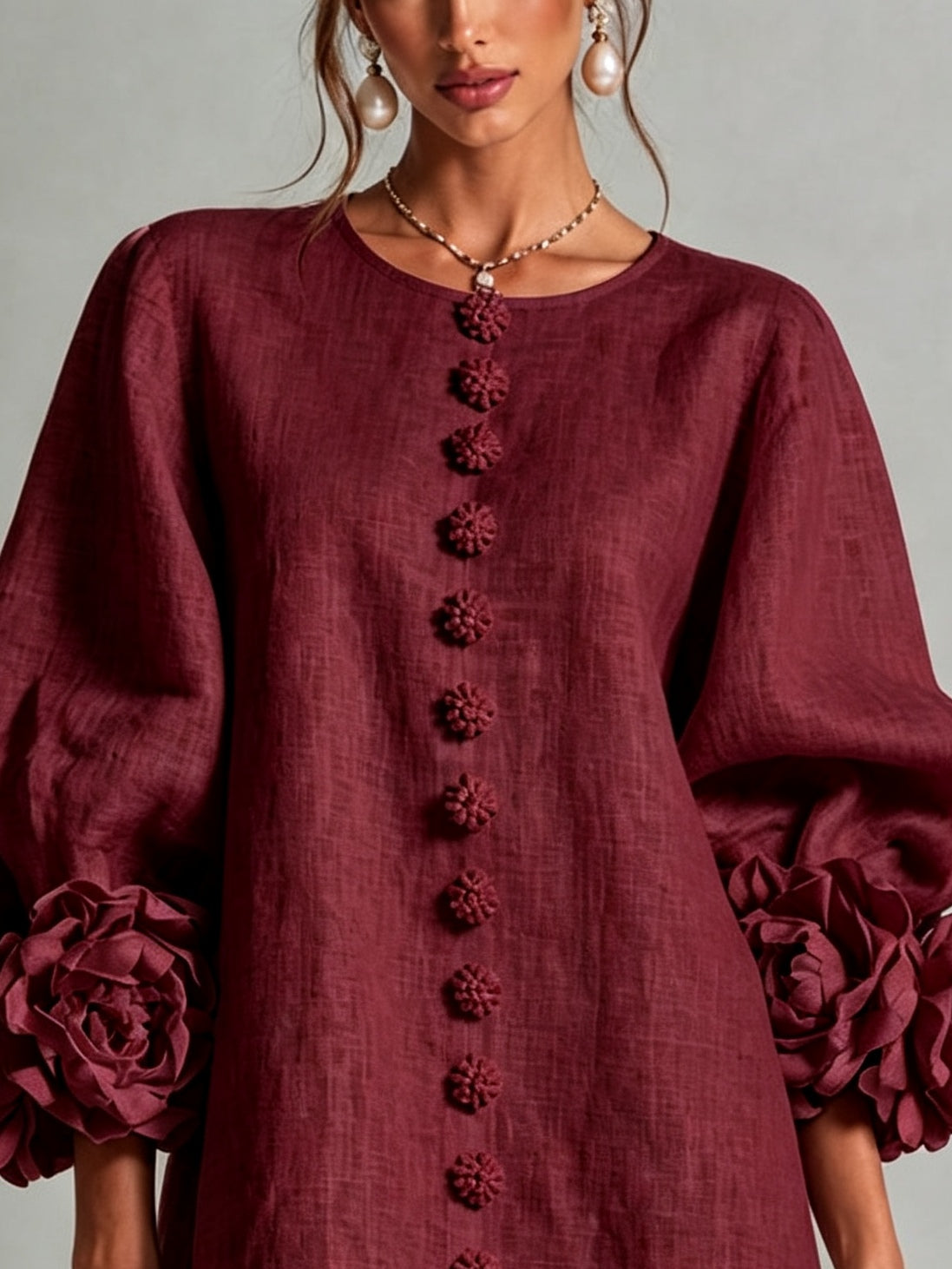 Close-up of burgundy midi dress: round neckline, textured fabric, and vertical embroidered trim