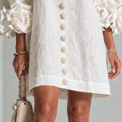 White button-front midi dress with gold buttons down center and rosette cuff puff sleeves