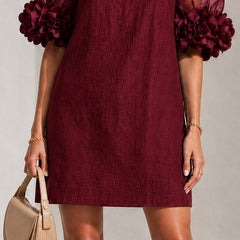 Burgundy textured shift dress with sheer puff sleeves and rosette pom-pom cuffs