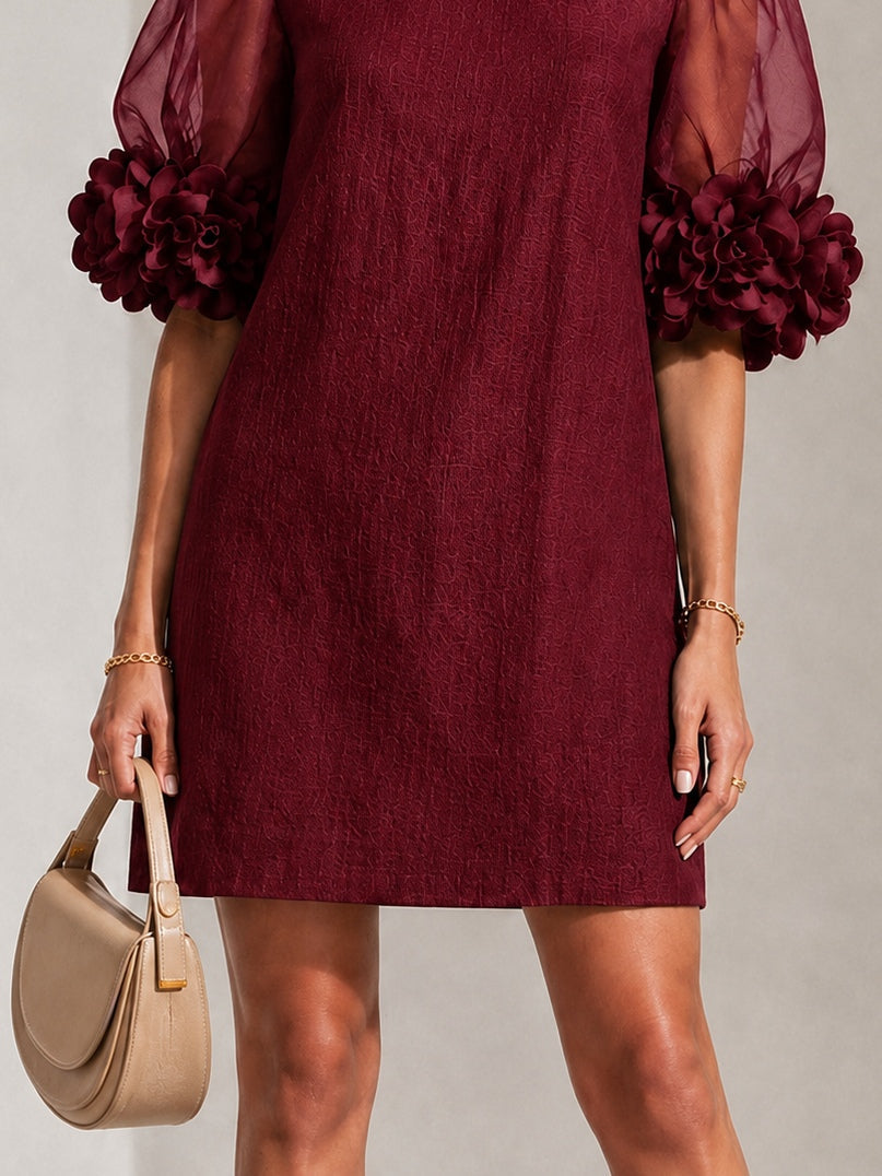 Burgundy textured shift dress with sheer puff sleeves and rosette pom-pom cuffs