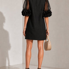 Black puff-sleeve midi dress, back view, sheer sleeves with rosette cuffs.