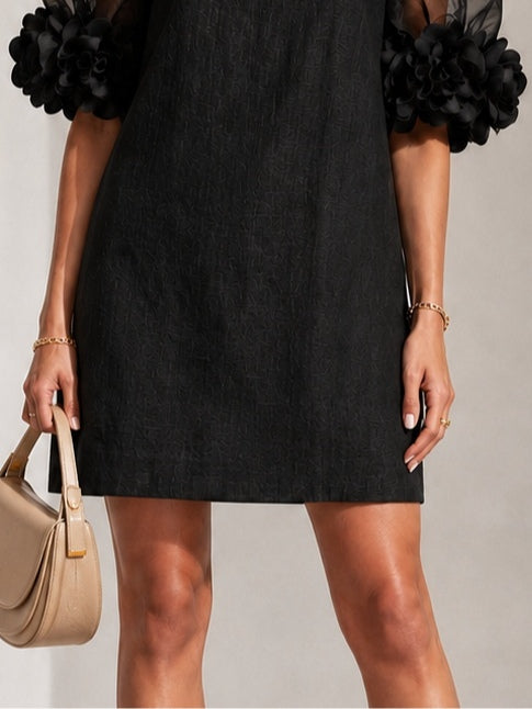 Black midi dress with sheer puff sleeves and rosette cuff embellishments, sleeved bodice.