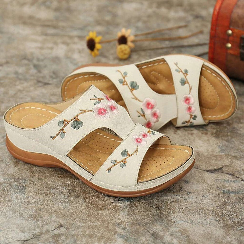 Sandali ortopedici bianchi con cinturini e ricami floreali rosa, suola marrone.