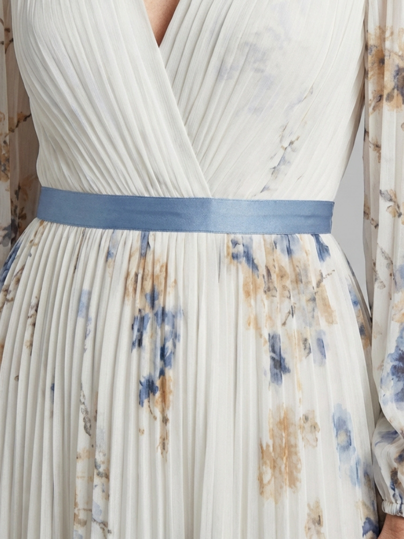 Pleated V-neck maxi dress close-up, blue waist sash over floral fabric