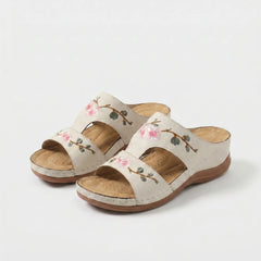 Sandali ortopedici beige con cinturini e ricami floreali rosa e steli verdi.