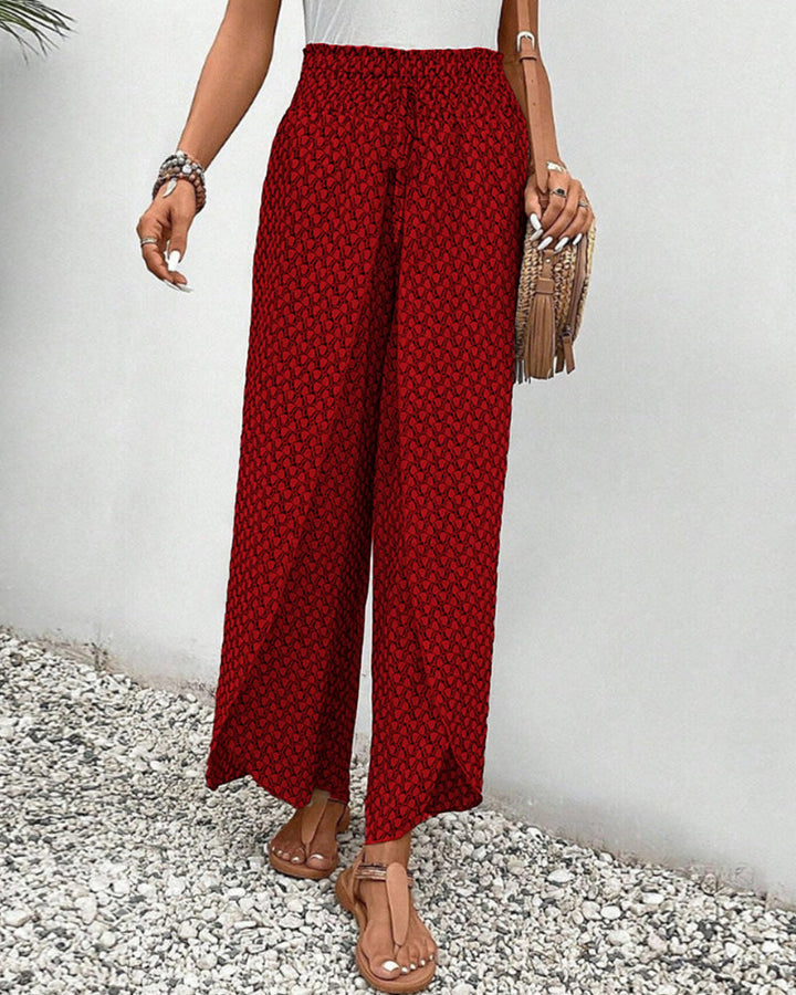 Red wide-leg trousers with shirred waist, flowing wide leg, repeating micro pattern.