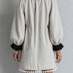 Beige puff-sleeve midi dress with black ruffled cuffs and bottom tassel trim