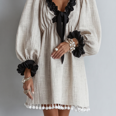 Beige midi dress with black puff sleeves, ruffled neckline, pearl bead details