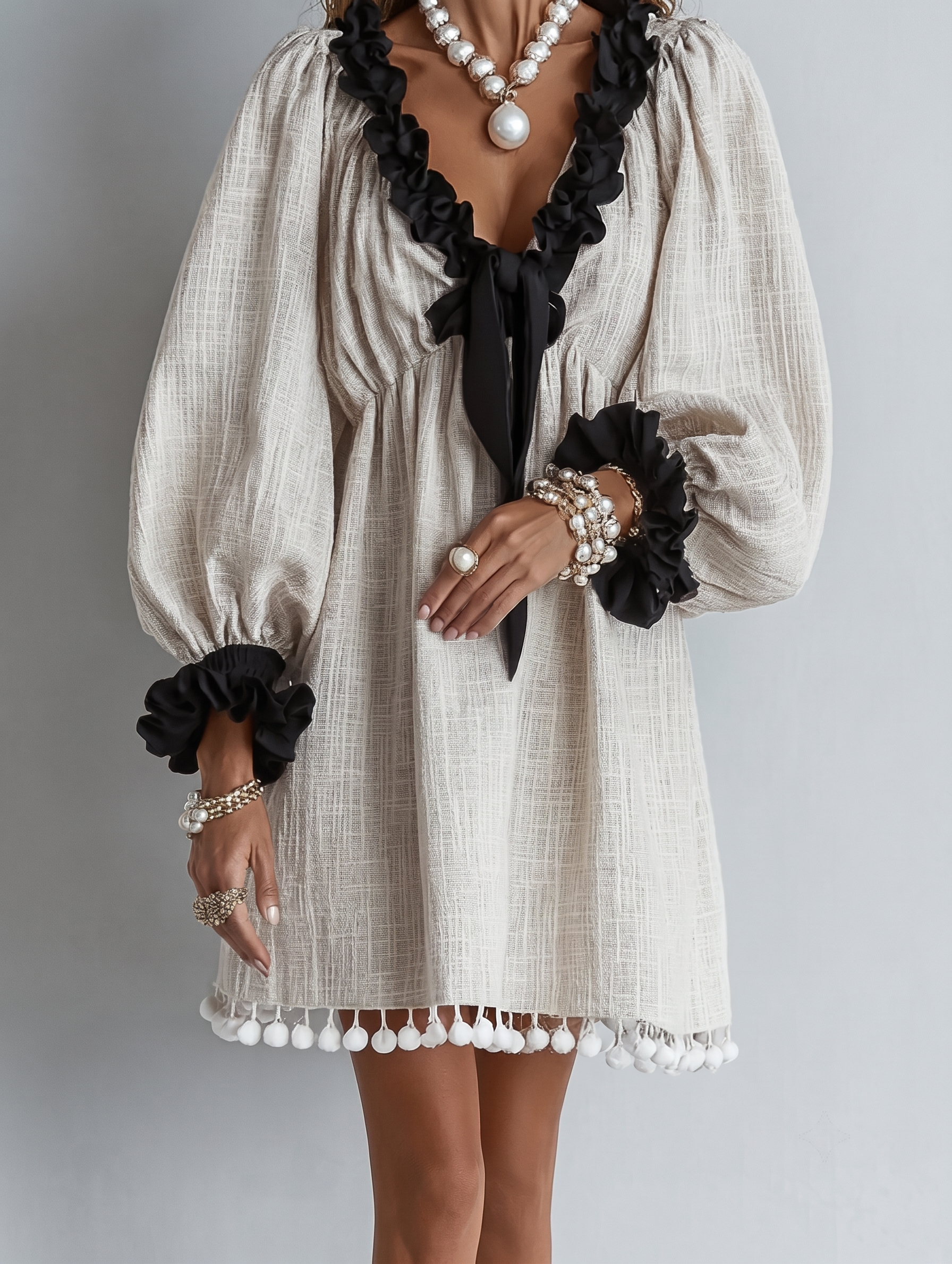 Beige midi dress with black puff sleeves, ruffled neckline, pearl bead details
